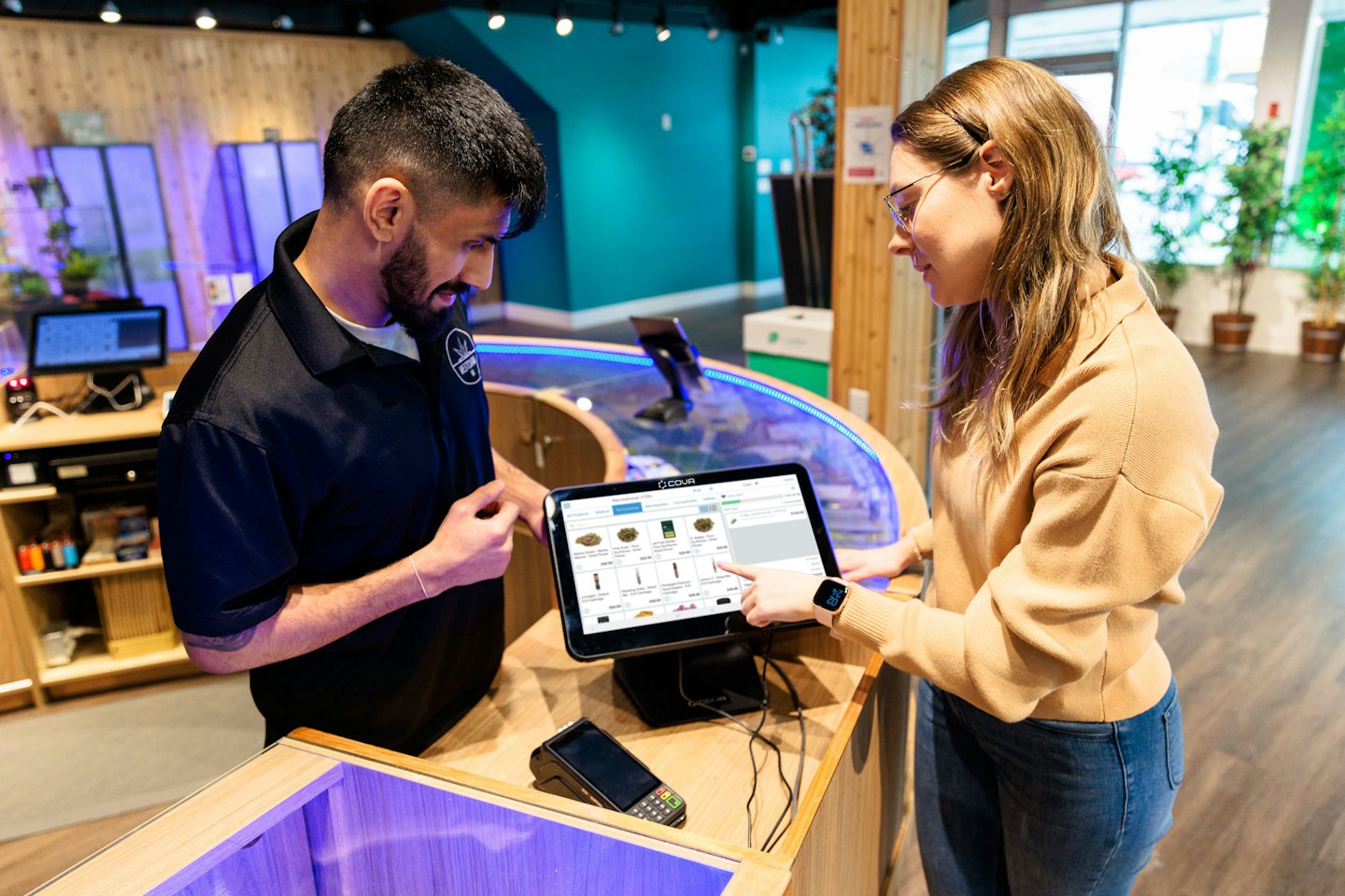 Sales associate helps customer choose products on touchscreen.